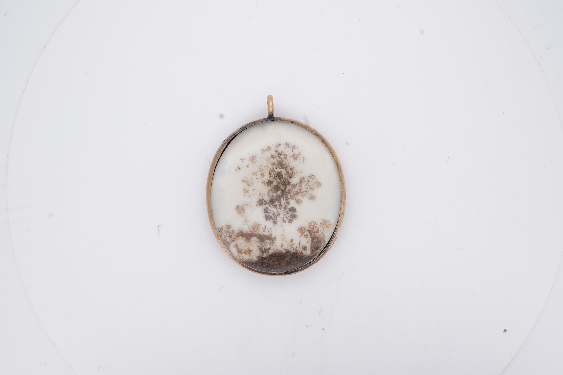 A 19th century gilt framed oval miniature watercolour portrait of a gentleman, on ivory, verso decorated with hair, depicting a landscape scene with a large tree, animals and a house, 36mm. CITES Submission reference, WU
